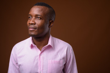 Fototapeta premium Studio shot of young African businessman against brown backgroun