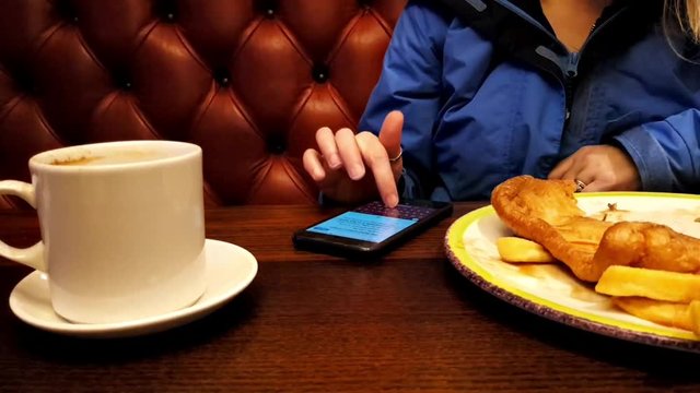 An adult using a mobile phone at the dinner table