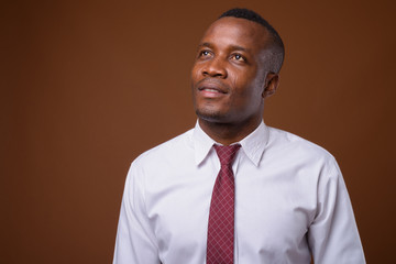 Studio shot of young African businessman against brown backgroun