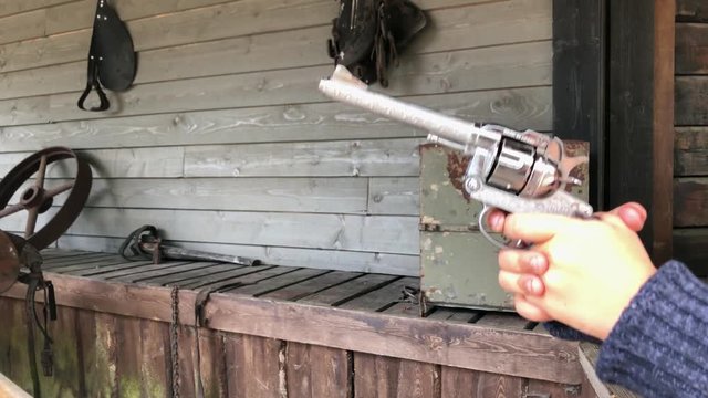 Cowboy kid in old wild west village pulls the trigger on a cap gun