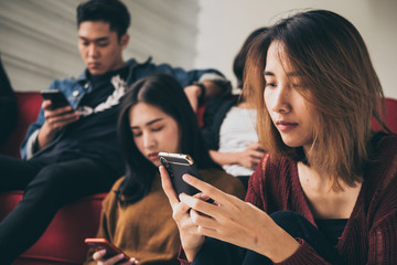 Asian People are focusing on smartphones while sitting together
