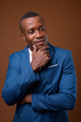 Studio shot of young African businessman against brown backgroun