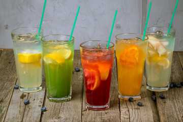 different lemonades in glasses on wooden background
