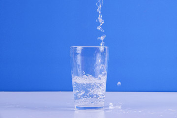Water splashing from glass isolated on a blue background.