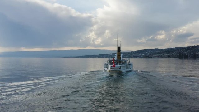 Drone shot orbiting behind Belle-Epoque steam boat on Lake L&radic;&copy;man, Switzerland at sunset
Mirror-like water and storm-clouds in the background