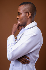 Studio shot of young African man doctor against brown background