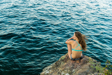 Beautiful young woman looking out at a lake.