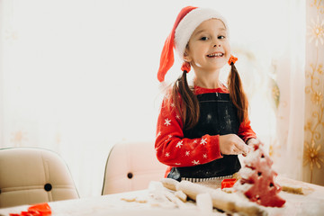 Smiling little girl at table making Christmas cookies
