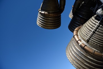 Several large powerful liquid fueled rocket engines against a clear blue sky. 