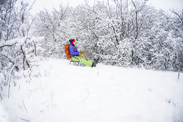 A girl on a sled rides from the mountain.
