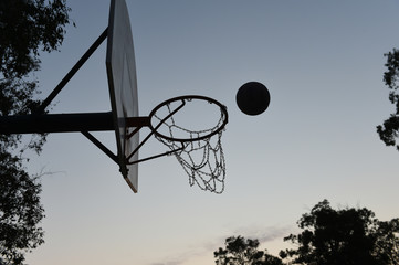 Silhouette of a basketball hoop and backboard at sunset