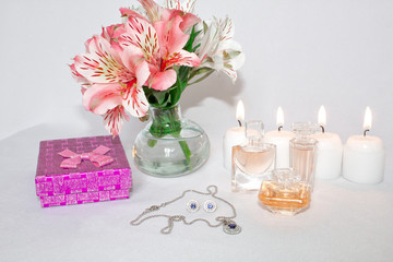Image of a pink luxury gift box with a bouquet of beautiful Alstroemeria flowers, romantic candles, perfume, jewelry and a credit card. Dressing table with women's accessories.