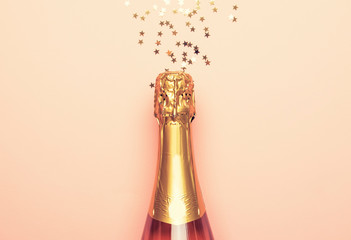 Christmas or New Year pink background with  bottle of sparkling wine, rose champagne and gold...