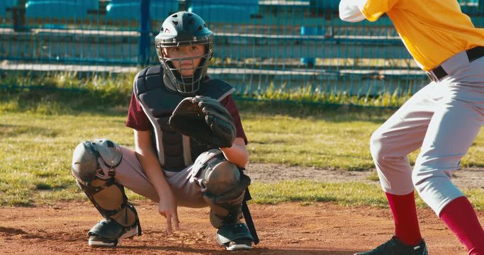 Baseball players batter and catcher kid boys baseball players prepare to receive a ball from pitcher. 4K UHD 60 FPS SLO MO RAW