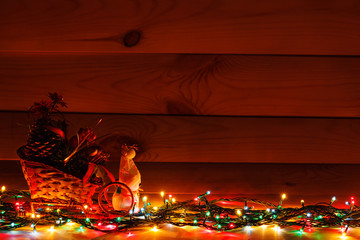 Christmas garland with a snowman in a sleigh with gifts. On wooden background