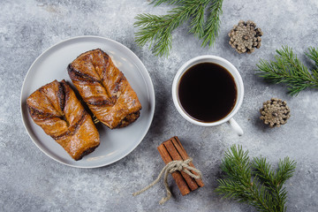 Christmas Breakfast Morning Concept. Christmas or New Year pastries with poppy seeds, warming black coffee, fir tree branches and cinnamon sticks. Flat lay, top view