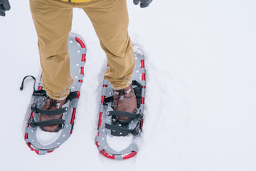 winter background, a pair of snowshoes with feet, standing on fluffy white snow