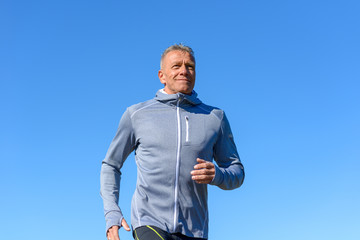 Gray smiling man running through a park