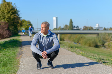 Obraz premium Middle aged runner sitting in a squat