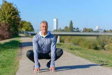 Middle aged runner sitting in a squat