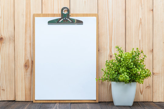 Clipboard blank white paper sheet with little decoration tree in white vase on wooden background, memo template design