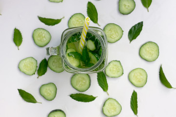Glass of delicious refreshing summer drink - cocktail of slices cucumber, ice, mint, straw , top view, closeup. 