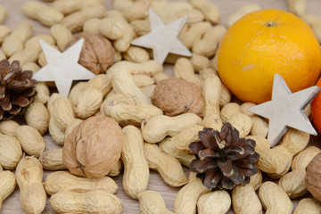 walnuts, tangerine, pine cone and peanuts on wood