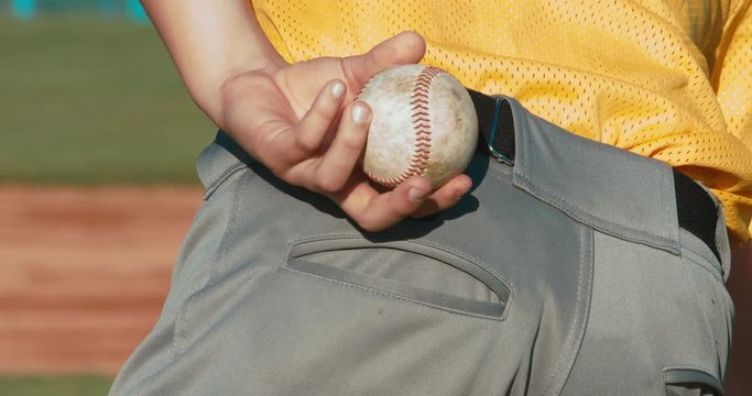 Kid boy baseball pitcher ready to pitch. Close up of hand focus on the fingers and the ball. 4K UHD