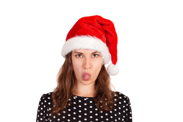 Dissatisfied brunette female model has disgusting expression, shows tongue, irritated with somebody. emotional girl in santa claus christmas hat isolated on white background