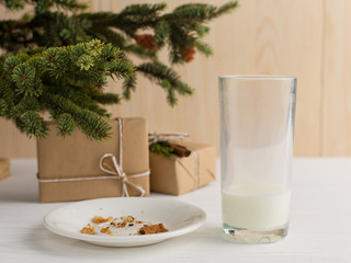 Empty glass of milk and crumb biscuits and a gift under the Christmas tree. The concept of the arrival of Santa Claus.