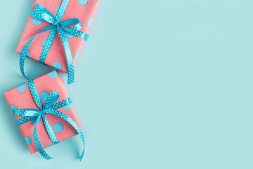 A gift wrapped in pink paper in a blue circle and ribbon, on a blue background. Copy space.