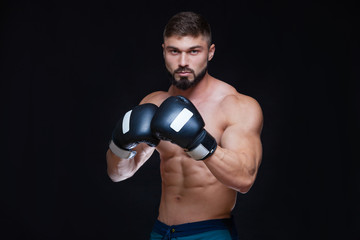 Fototapeta na wymiar Strong muscular boxer in black boxing gloves. Isolated on black background.