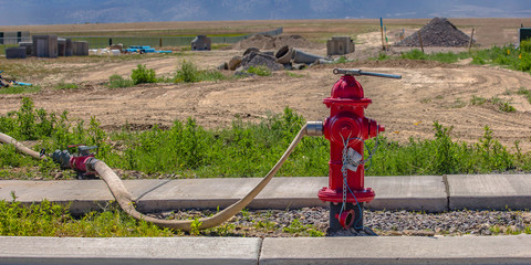 Red fire hydrant with connected hose and wrench