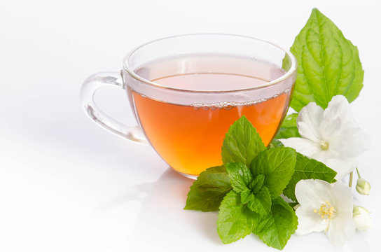 Glass cup of Tea with jasmine flowers and leaves of mint
