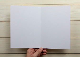 Mens hands holding empty white booklet