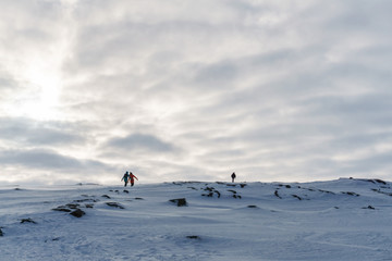 people in bright jackets go somewhere far along the snowy peaks of the tundra on a frosty winter day during a trip to the arctic
