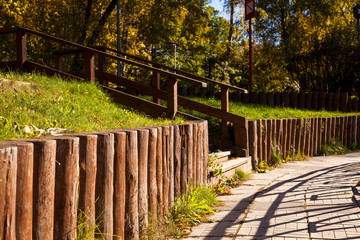 Log fence, wooden staircase and tiled path on the slope in the Park