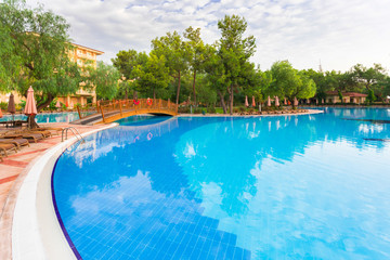 Luxury hotel with a large green area and a huge pool and sun beds around it. Relaxation and luxury beach holidays