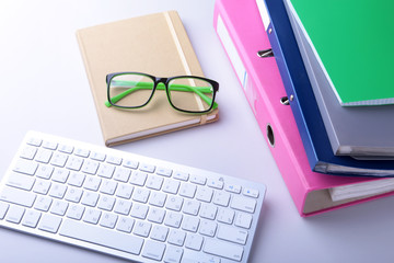 Office desk table with blank notebook, keyboard, other supplies and coffee cup. Top view with copy space