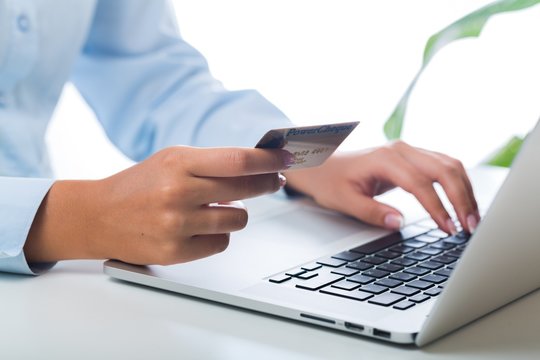 Closeup of a Woman Typing on a Laptop and Holding a Credit Card