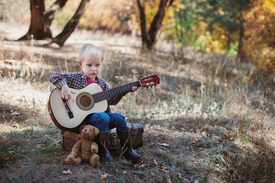 Boy playing guitar in autumn forest