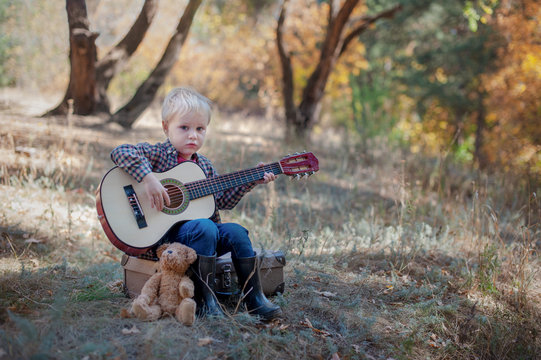 Boy playing guitar in autumn forest