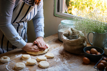 Woman kneading dough to make donuts - obrazy, fototapety, plakaty