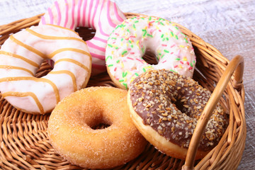Wicker basket with assorted delicious homemade doughnuts in the glaze, colorful sprinkles and nuts .