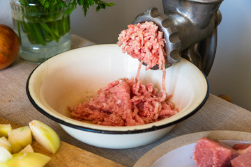 Mincer and mixed chicken and pork mince on a rustic background