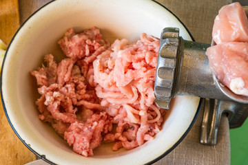 Mincer and mixed chicken and minced pork on a rustic background close up, top view