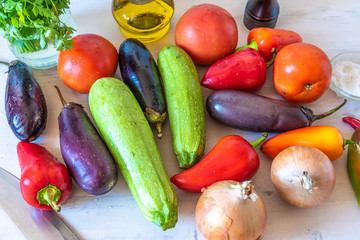 Fototapeta na wymiar Fresh raw rustic vegetables for vegetable stew - eggplants, zucchini, tomatoes, onions, peppers, top view