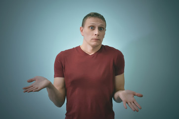 Guilty man is standing and is shrugging his shoulders isolated on blue background.