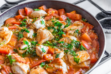 Chicken cacciatore is cooked in a frying pan, chicken stew with tomatoes and red pepper - top view