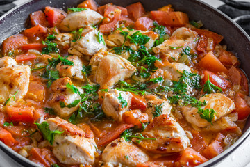Chicken cacciatore is cooked in a frying pan, chicken stew with tomatoes and red pepper - top view